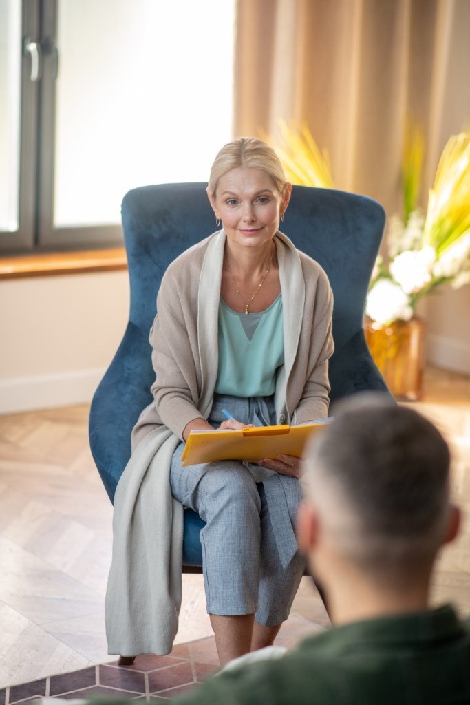 Beautiful psychologist sitting in armchair and helping patient